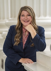 CA Assemblymember Tasha Boerner stands near pillar outside of CA statehouse, holding her hand under her chin, elbow resting on wall
