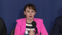 New NTIA chief Arielle Roth sits in front of microphone during nomination hearing wearing a pink jacket over a striped shirt