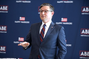 House Speaker Mike Johson holds his hand flat out jutting out as he speaks to a crowd