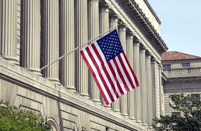 US Commerce Department building with US flag hanging in front of pillars