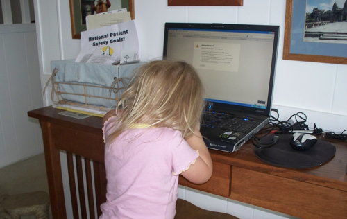 A little blonde girl sits in front of computer holding her face in her hands, distressed that the screen says has no Internet service while trying to do school work