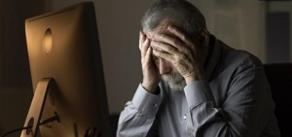 Holding head frustrated at computer screen