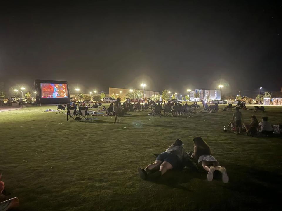 Residents lay in athletic field under lights at night event