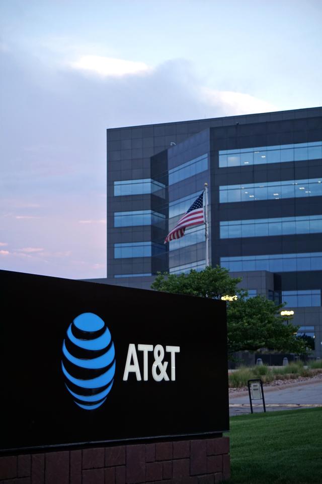 A vertical shot of a modern office building displaying the AT&T logo and the American flag.