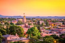 An aerial view of a city in New Mexico at dusk with a picturesque mountain scape in the background