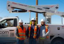Three Wecom technicians stand next to a Wecom truck smiling during construction of fiber network in Flagstaff